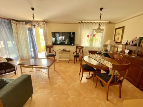 Spacious living area in Retiro Playa & Spa Apartment with dining table, wooden furniture, TV, and terrace views in Almagro
