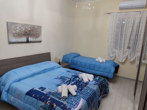 Due letti blu con asciugamani bianchi in un luminoso appartamento vacanziero a La Maison Du Port, Licata, con aria condizionata e arredamento moderno