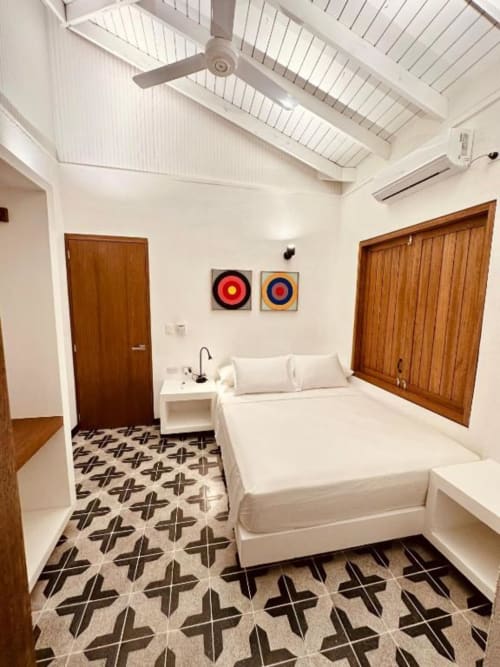 Dormitorio moderno en lodge boutique Seaflower con cama blanca, puertas de madera, suelo con patrón y ventilador de techo