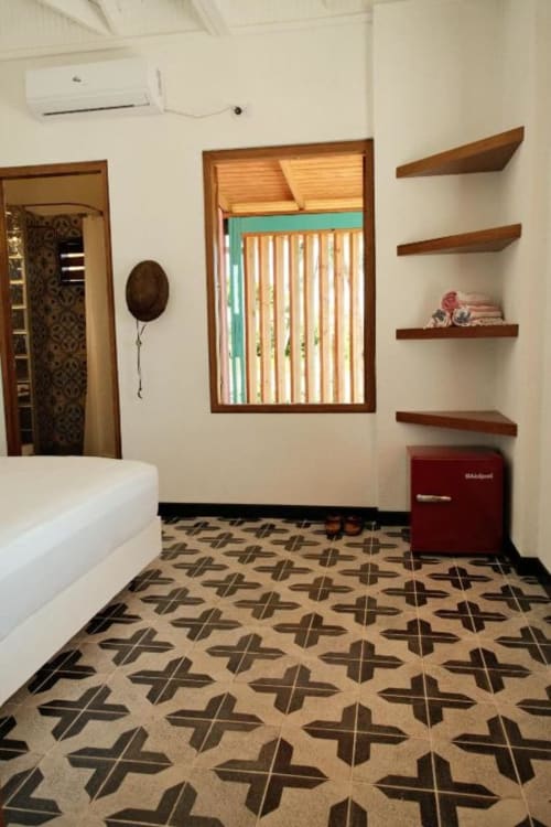 Habitación moderna en lodge boutique Seaflower con estantes de madera, cama blanca y piso de azulejos estampados en San Andrés