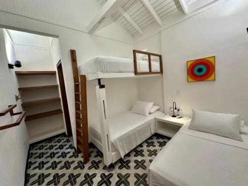 Dormitorio luminoso en el lodge boutique Seaflower con cama litera, cama individual, escalera de madera, patrón geométrico en el piso, y