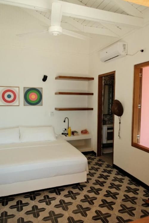 Dormitorio moderno del hotel boutique Seaflower en San Andrés con cama blanca, estantes de madera y piso con patrón geométrico