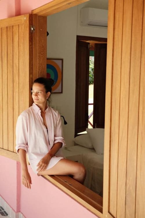 Mujer con camisa rosa en la posada Seaflower, San Andrés, con puertas de madera y habitación con vista al mar