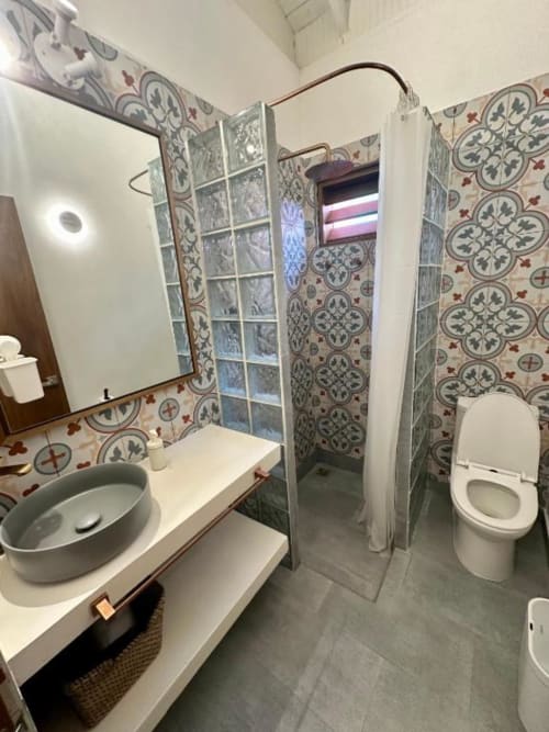 Baño moderno del boutique hotel Seaflower en San Andrés con paredes decoradas en azulejos, lavamanos de cerámica y ducha de cristal