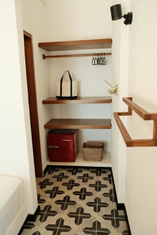 Armario de lavandería con estantes de madera, plancha, ganchos y piso con patrón geométrico en Seaflower boutique lodge, San Andrés
