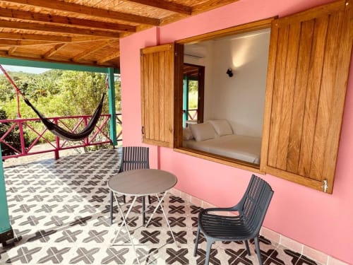 Habitación de la boutique Seaflower con paredes rosadas, muebles de madera, terraza con hamaca y vistas al mar en San Andrés