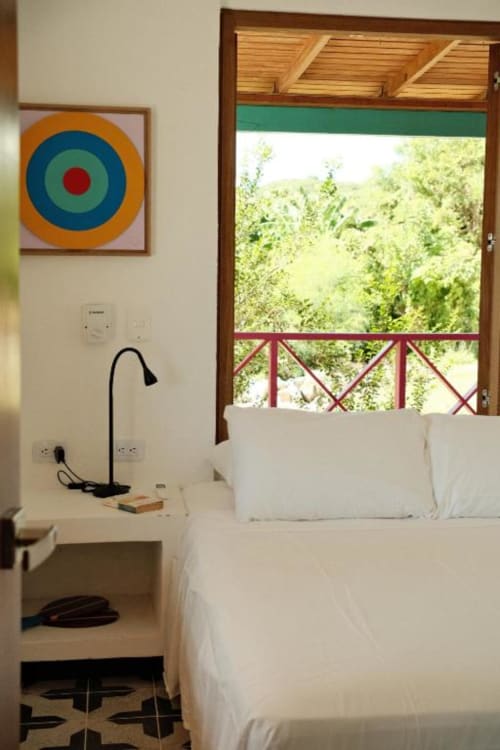 Dormitorio luminoso en Seaflower lodge con ropa de cama blanca, arte colorido, detalles de madera y vistas al mar