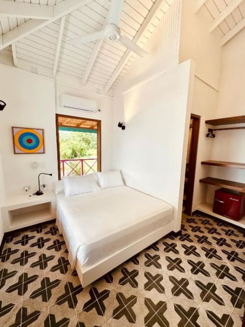 Dormitorio luminoso en el boutique lodge Seaflower con cama blanca, suelo geométrico, techo de vigas de madera y vistas al mar