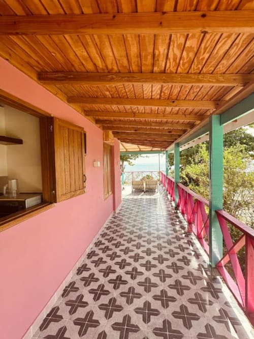 Pórtico colorido del boutique hotel Seaflower con paredes rosa, vigas de madera y piso de azulejos decorativos con vista al mar