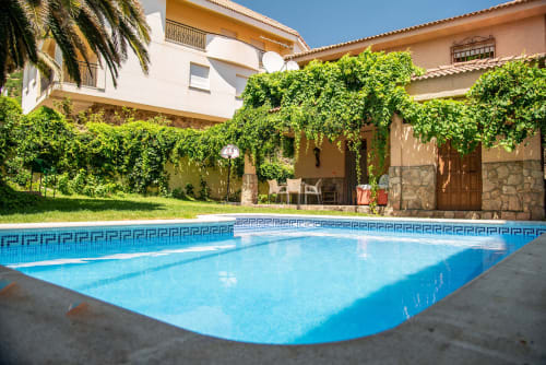Crystal-clear swimming pool at Casa Rural Villa del Jerte in El Torno, Cáceres, with ivy-covered courtyard and rustic