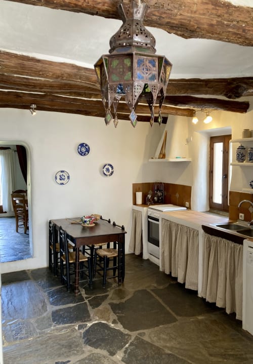 Amplia y cómoda cocina tradicional Alpujarreña con vigas de castaño, mesa comedor y detalles de decoración de Casa Josefa Capileira