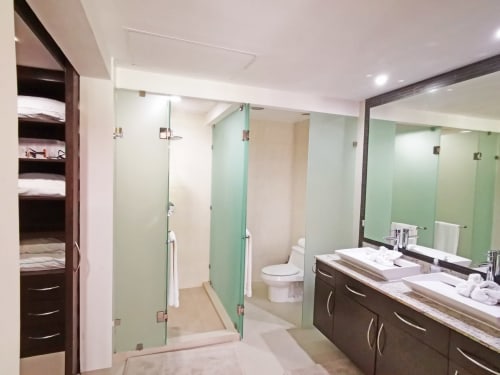 Baño moderno en Mareazul Resort con vista al mar, doble lavamanos, ducha de vidrio y azulejos verdes decorativos
