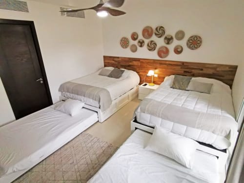 Moderna habitación en Mareazul Condo Paraíso con dos camas, cabecero de madera, platos decorativos, ventilador de techo y vista al mar