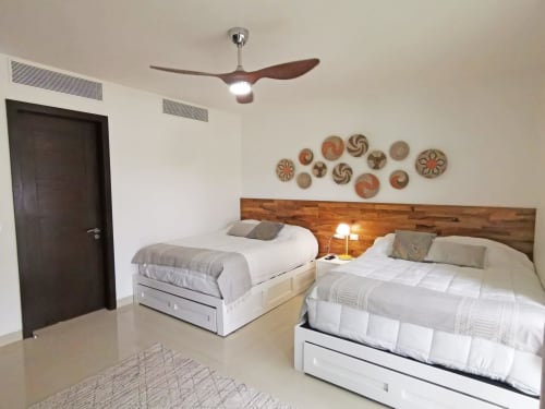 Habitación moderna en Mareazul Resort Playa del Carmen con camas gemelas, cabecera de madera, ventilador de techo y canastas decorativas en la pared