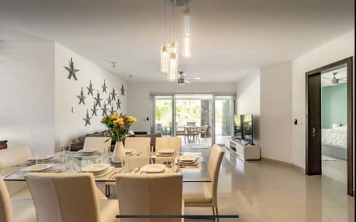 Comedor moderno en el resort frente al mar Mareazul con elegante mesa puesta, decoración de estrellas en la pared y puertas con vista al jardín en Playa