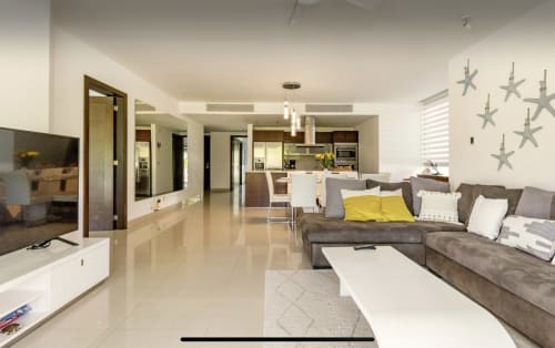 Moderno condo en planta abierta en Mareazul Resort, Playa del Carmen, con sofá gris y cojines amarillos, TV de pantalla plana