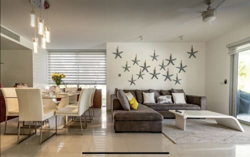Área de estar en plano abierto en Mareazul Playa del Carmen con sofá seccional gris, mesa de comedor y decoración con estrellas de mar