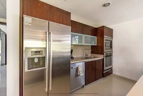 Cocina moderna con electrodomésticos de acero inoxidable, gabinetes de madera oscura y encimeras de granito en Mareazul