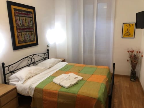Bright double bedroom at Maison Vaticana Rome with colorful patchwork bedcover, white pillows, and wrought iron bed frame