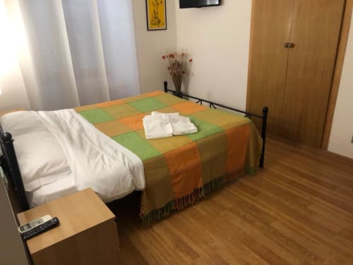 Double room at Maison Vaticana Guest House Rome with bed, colorful bedspread, TV, and wooden wardrobe