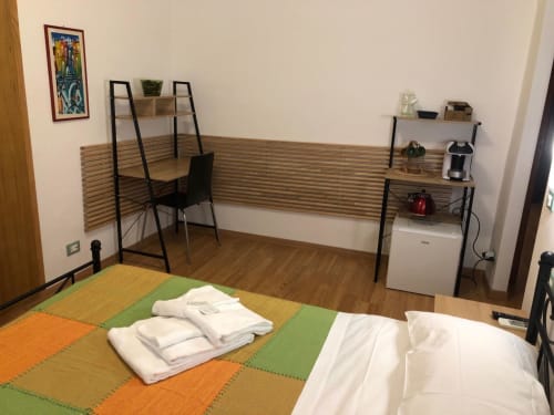 Double Room D1 at Maison Vaticana Guest House Rome featuring work desk, shelving, colorful floor mats, and white linens