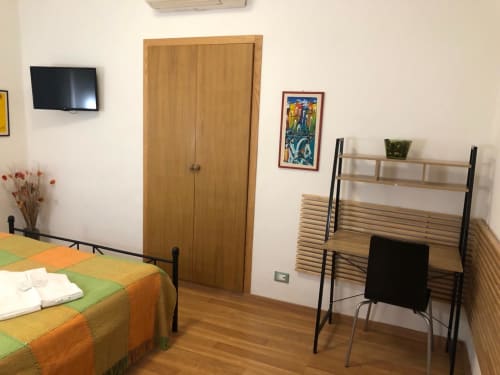 Bright Double Room D1 at Maison Vaticana Guest House Rome with wooden bed, desk, shelving, TV and minimalist decor