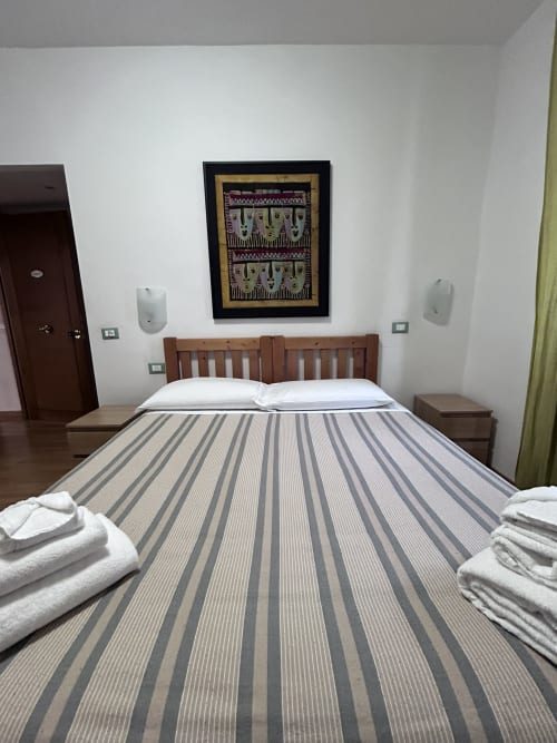 Double room at Maison Vaticana Guest House Rome with striped bedding, wooden headboard, and framed artwork