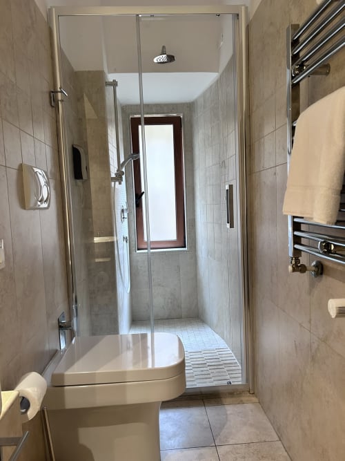Modern bathroom in Maison Vaticana Rome with walk-in shower, toilet, and heated towel rail
