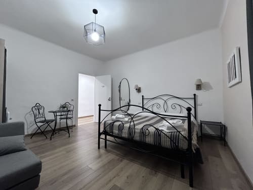 Modern double bedroom at Maison Vaticana Guest House Rome with black metal bed, wooden flooring, and contemporary furnishings