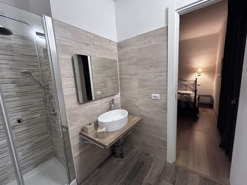 Modern bathroom in Maison Vaticana Rome with vessel sink, walk-in shower, and wood-style tile walls