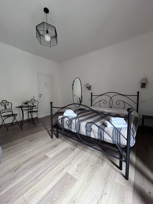 Modern bedroom at Maison Vaticana Rome with metal bed frame, striped bedding, and minimalist décor on wooden flooring