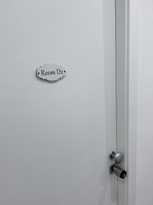 Room D2 door with nameplate at Maison Vaticana Guest House Rome, showing metal handle and white textured wall