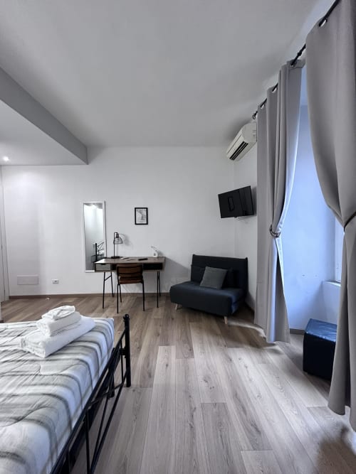 Modern suite at Maison Vaticana Guest House Rome with bed, desk, TV, and seating area