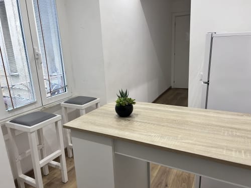 Modern dining area in Maison Vaticana Rome suite with light wood table, white bar stools, and potted plant
