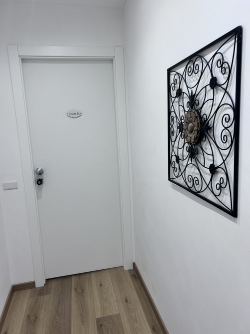 Hallway in Maison Vaticana Rome with white door labeled Room S2 and decorative black wrought iron wall clock