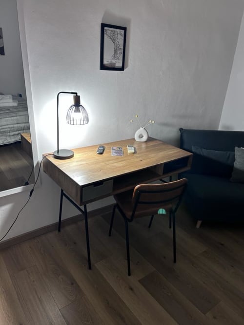Modern workspace desk with wooden top, black desk lamp, white vase, and chair in Maison Vaticana Rome guest suite