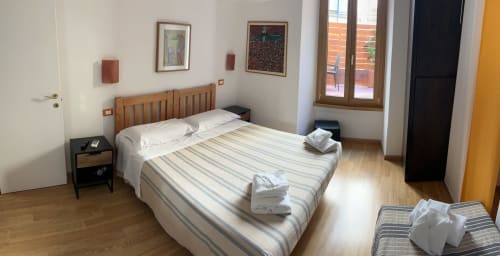 De Luxe Double Room at Maison Vaticana Guest House Rome with wood bed, striped bedding, and modern amenities