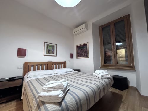 De Luxe Double Room at Maison Vaticana Guest House Rome with wooden bed, striped bedding, and modern amenities