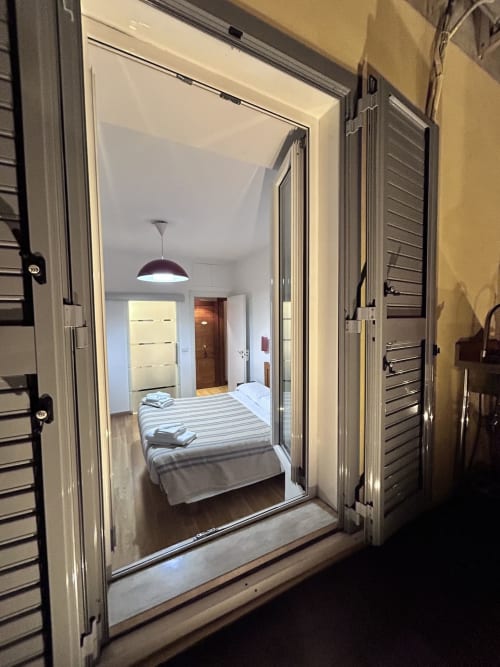De Luxe Double Room D3 at Maison Vanicana Guest House Rome, viewed through open glass doors with striped bedding and pendant
