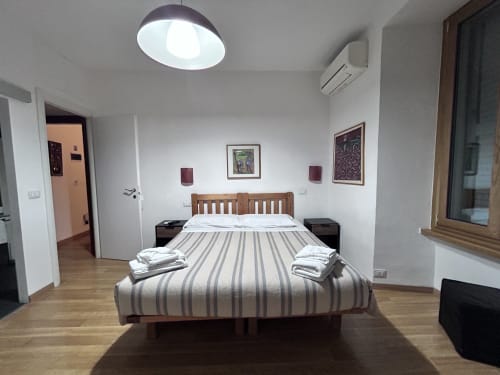 Spacious De Luxe Double Room at Maison Vaticana Guest House Rome with wooden bed, modern amenities and bright ceiling light