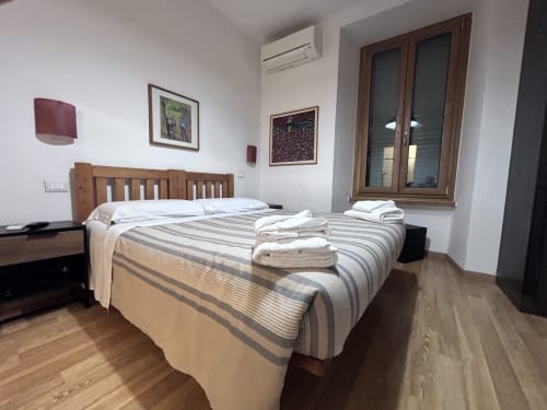 De Luxe Double Room at Maison Vaticana Guest House Rome with wooden bed, striped bedding, wood flooring, and modern amenities