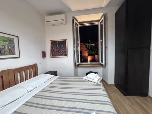 Maison Vanicana Rome De Luxe Double Room with striped bedding, wooden headboard, open window with plant, and framed wall art