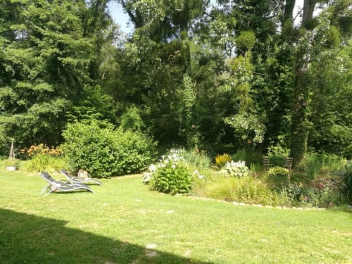 Jardin ensoleillé avec pelouse verdoyante, transat et massifs fleuris au Clos du Buisson, Saint Aubin sur Gaillon