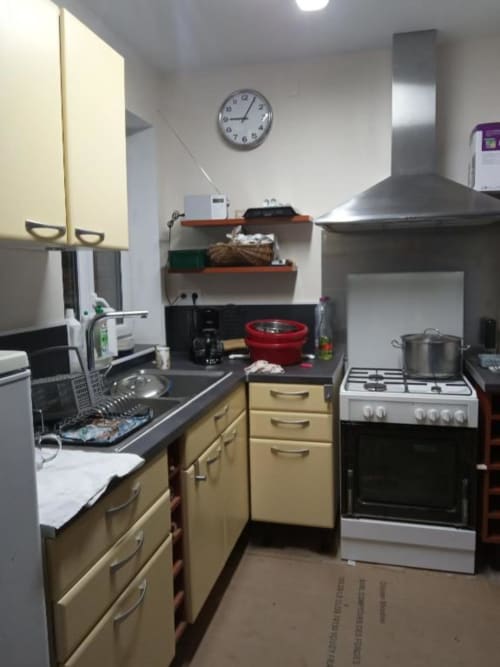 Cuisine bien équipée, du BnB Le Clos du Buisson avec meubles crème, cuisinière, évier et horloge murale