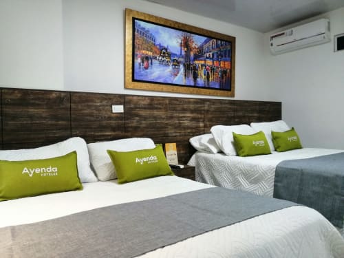 Habitación moderna del Hotel Maderos Cali con dos camas, almohadas verdes Ayenda, cabecero de madera oscura y TV de pantalla plana