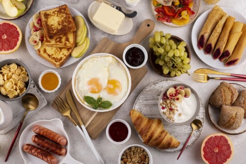 Brunch apetissant sur une table remplie de mets. Brioche saucisses œufs et fruits.