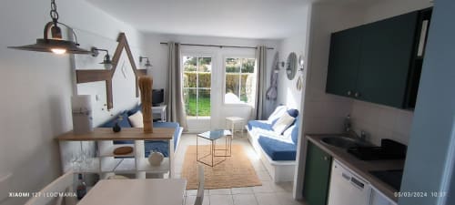 Studio lumineux à Loc'Maria, Belle-Île-en-Mer avec mobilier bleu, coin repas, TV et portes vue jardin
