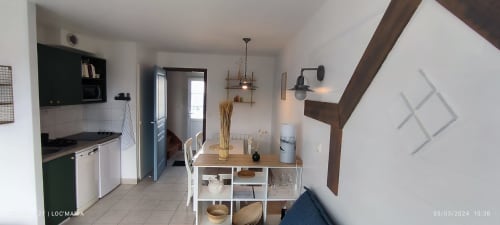 Cuisine-séjour moderne à Loc'Maria, Belle île en mer, avec poutres en bois, étagères blanches et table à manger
