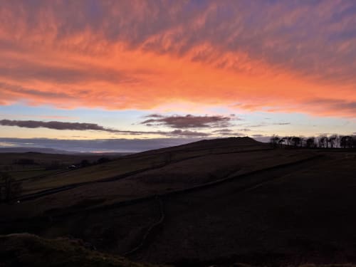 Stunning sunset over rolling hills near Haydon Bridge, Hexham, with dramatic orange and purple clouds