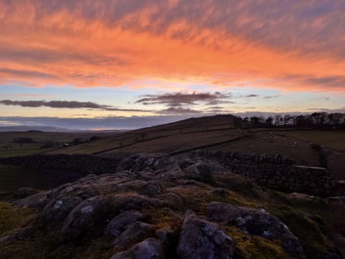 Sunset over rolling countryside near Haydon Bridge, Hexham, with rocky outcrops and stone walls